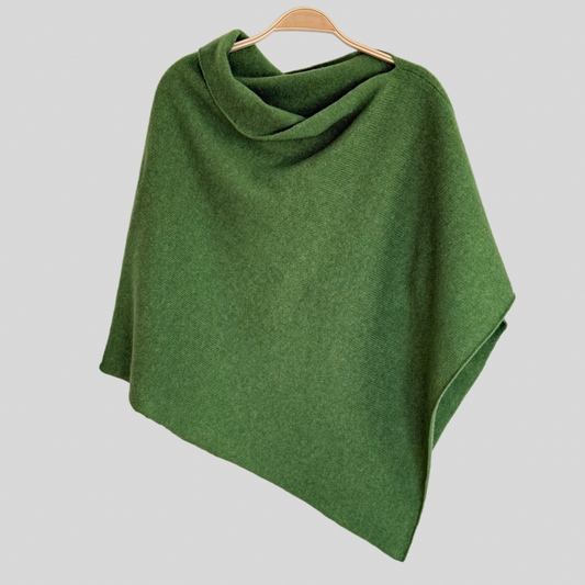 A green merino lambswool poncho displayed on a wooden hanger, with a draped and angled cut that covers the shoulders.