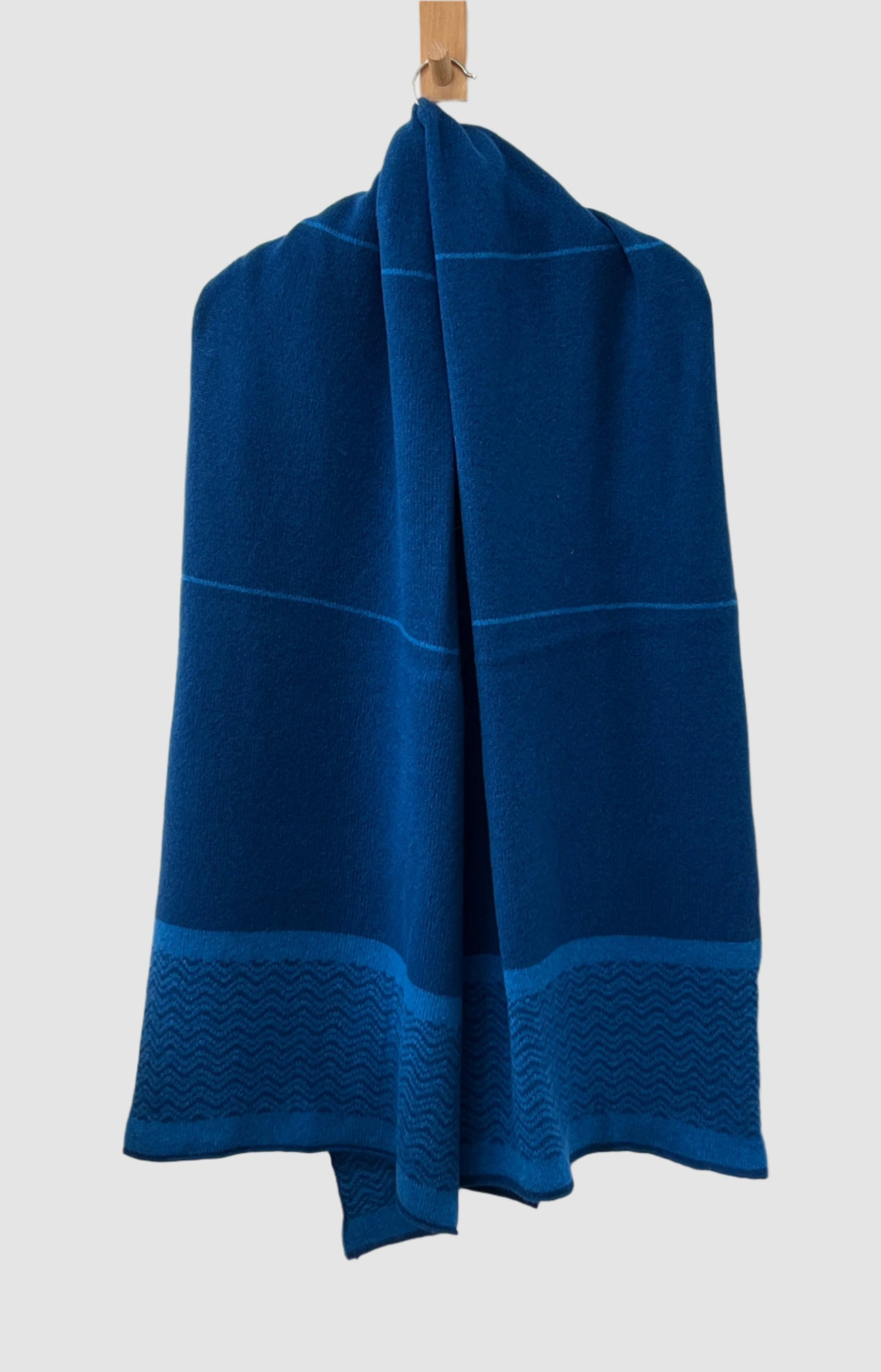 FinesseKnits malabar blue and Neptune blue shawl scarf with a wave pattern and stripes, draped over a hanger.