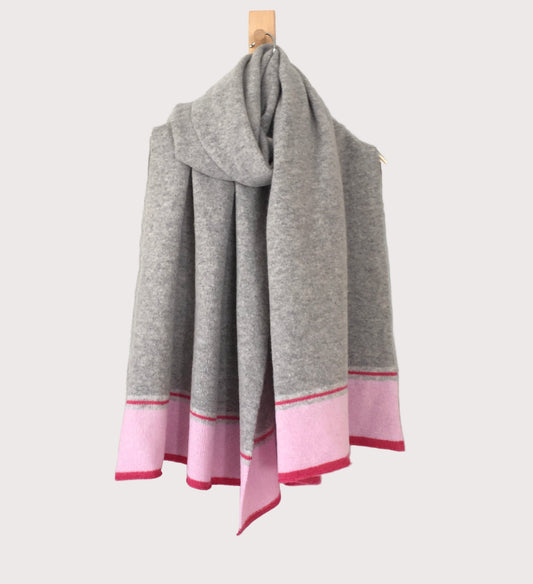A silver grey scarf with blush pink and pink ends draped over a hanger.